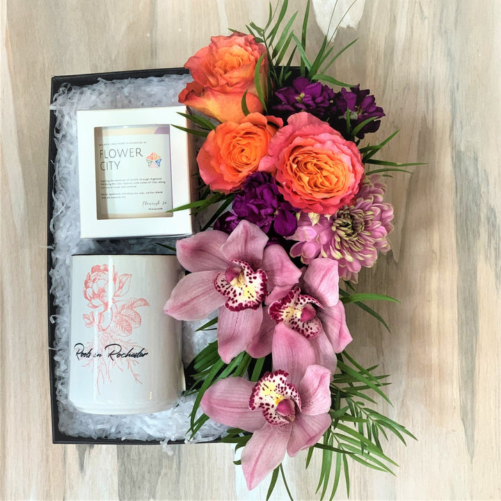 Spring Roc Gift box with fresh florals, Roots in Rochester Mug, and Flourish Co. Flower City candle. Photo taken against wooden background.