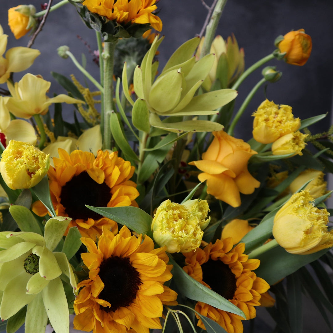 Yellow sunflowers, yellow tulips, yellow safari protea and greeney.