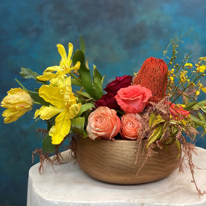 yellow, orange and peach centerpiece with protea and garden roses in a ceramic bowl